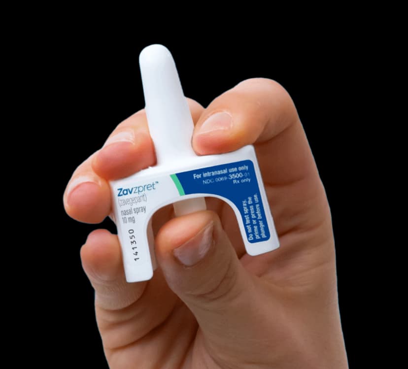 Zavzpret zavegepant nasal spray device held in hand showing single-dose intranasal applicator for acute migraine treatment